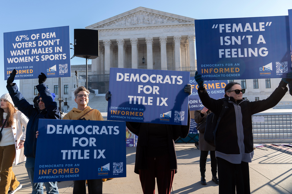 Protesters gather outside the Supreme Court as it hears arguments over state laws barring transgender girls and women from playing on school athletic teams, Tuesday, Jan. 13, 2026, in Washington. (AP Photo/Jose Luis Magana)