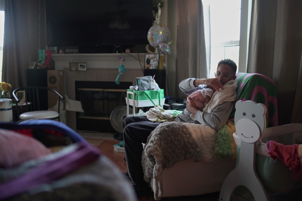 JaKobi Burton cradles his newborn daughter, Phoenix RyZen Reign Burton, on his shoulder at his home in Indianapolis, Nov. 13, 2025. (AP Photo/Obed Lamy)