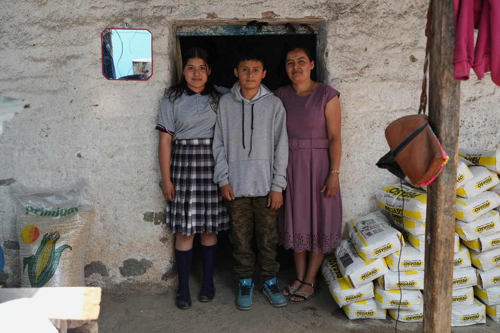Mirsy Maricela Alva López, right, and her children, Ederson, center, and Briseidy pose for photos at their house in San Martín Cuchumatán, Guatemala, Thursday, April 30, 2026. (AP Photo/Moises Castillo)