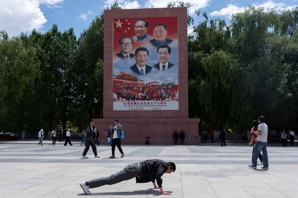 A man performs push-ups near a large mural depicting Chinese President Xi Jinping, bottom center, and other Chinese leaders at a public square at the base of the Potala Palace in Lhasa in western China's Tibet Autonomous Region on Tuesday, July 21, 2026, as seen during a government organized visit for foreign journalists. (AP Photo/Ng Han Guan)