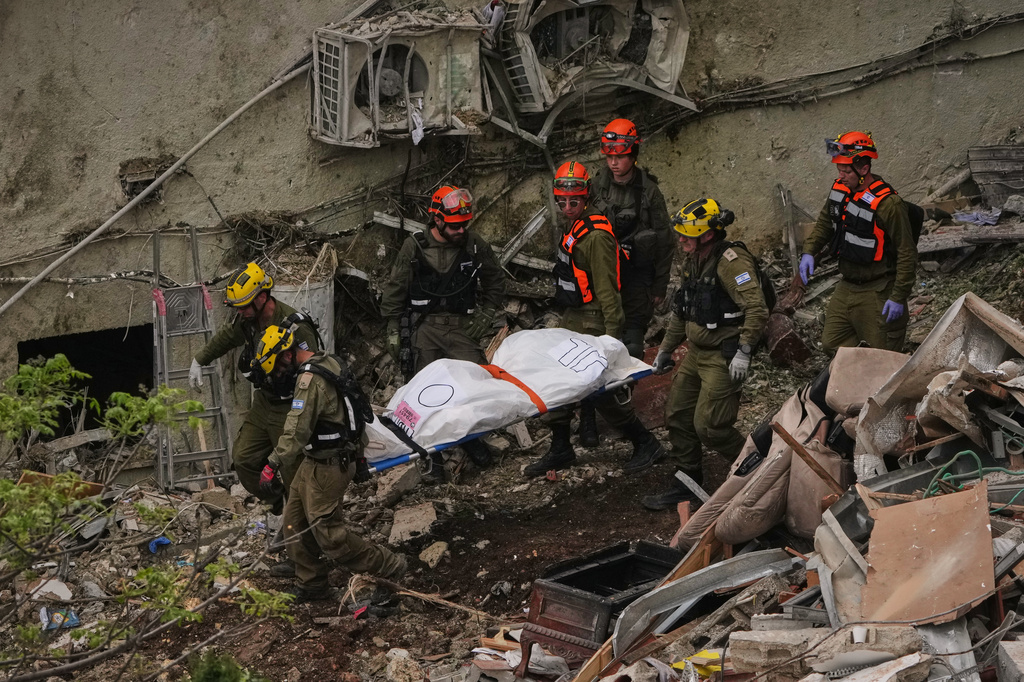 Rescue workers and military personnel carry a body of a victim from the rubble of a residential building a day after it was struck by an Iranian missile in Haifa, Israel, Monday, April 6, 2026. (AP Photo/Ariel Schalit)
