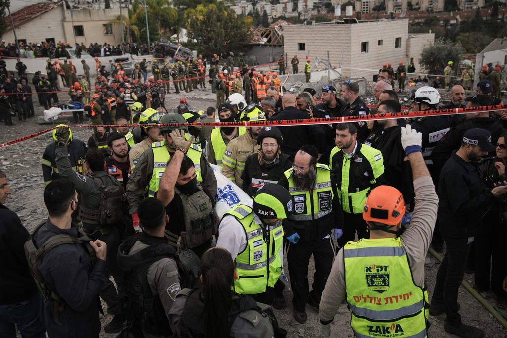 FILE - Rescue workers and military personnel carry a body of a victim from the scene where several people were killed by an Iranian missile strike in Beit Shemesh, Israel, Sunday, March 1, 2026. (AP Photo/Leo Correa, File)