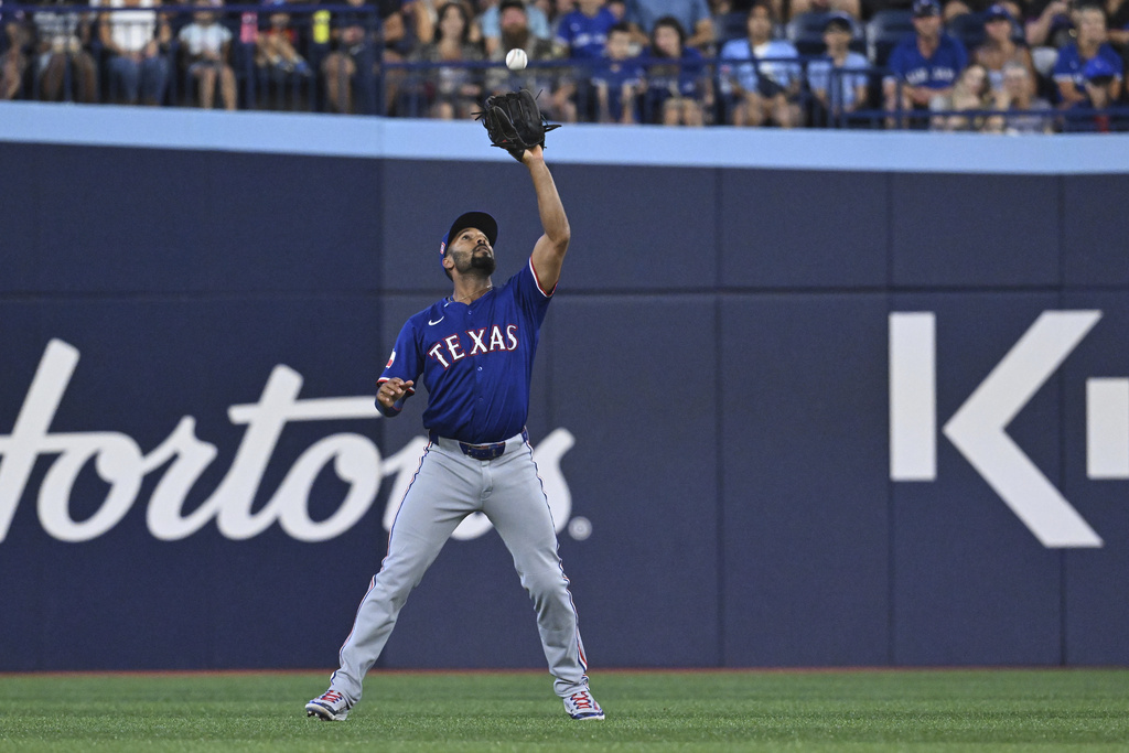 Texas Rangers second baseman Marcus Semien catches a fly ball off the bat of Toronto Blue Jays' George Springer in first-inning baseball game action in Toronto, Sunday, Aug. 17, 2025. (Jon Blacker/The Canadian Press via AP)