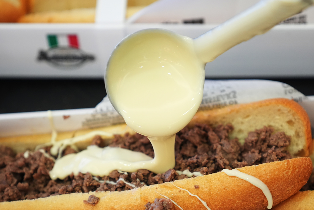 A volunteer ladles out cheese onto one of many cheesesteaks as part of a Guinness World Record attempt on National Cheesesteak Day at Philadelphia International Airport, in Philadelphia, Tuesday, March 24, 2026, in Philadelphia. (AP Photo/Matt Rourke)