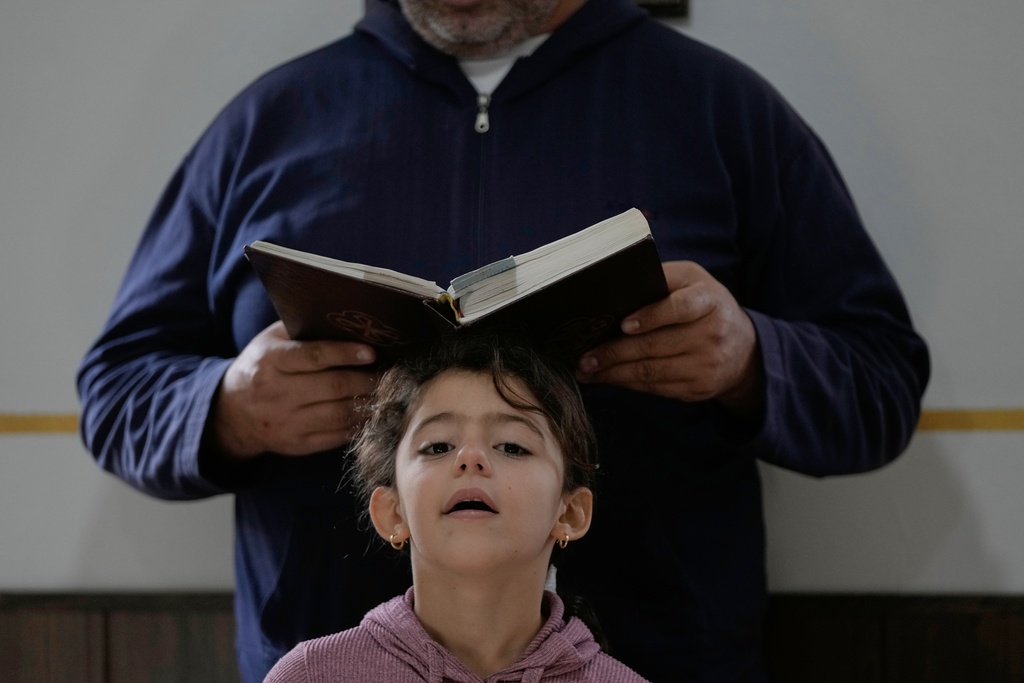A girl gestures as her family attends Sunday Mass inside a room usually used as a residence for visiting bishops next to St. George Melkite Catholic Church, which was destroyed in an Israeli airstrike, in the town of Dardghaya, southern Lebanon, Sunday, Nov. 16, 2025. (AP Photo/Hassan Ammar)