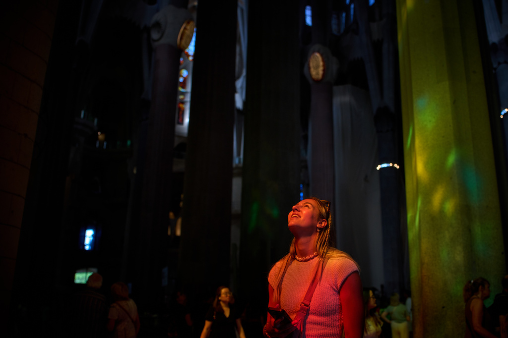A visitor, bathed in sunlight streaming through the stained-glass windows, gazes up at the ceiling of the Sagrada Familia in Barcelona, Spain, Tuesday, May 26, 2026. (AP Photo/Emilio Morenatti)