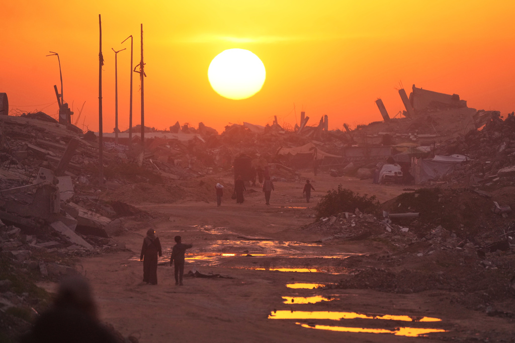 Palestinians walk through the ruins of destroyed buildings as the sun sets over Gaza City, Sunday, Jan. 4, 2026. (AP Photo/Jehad Alshrafi)