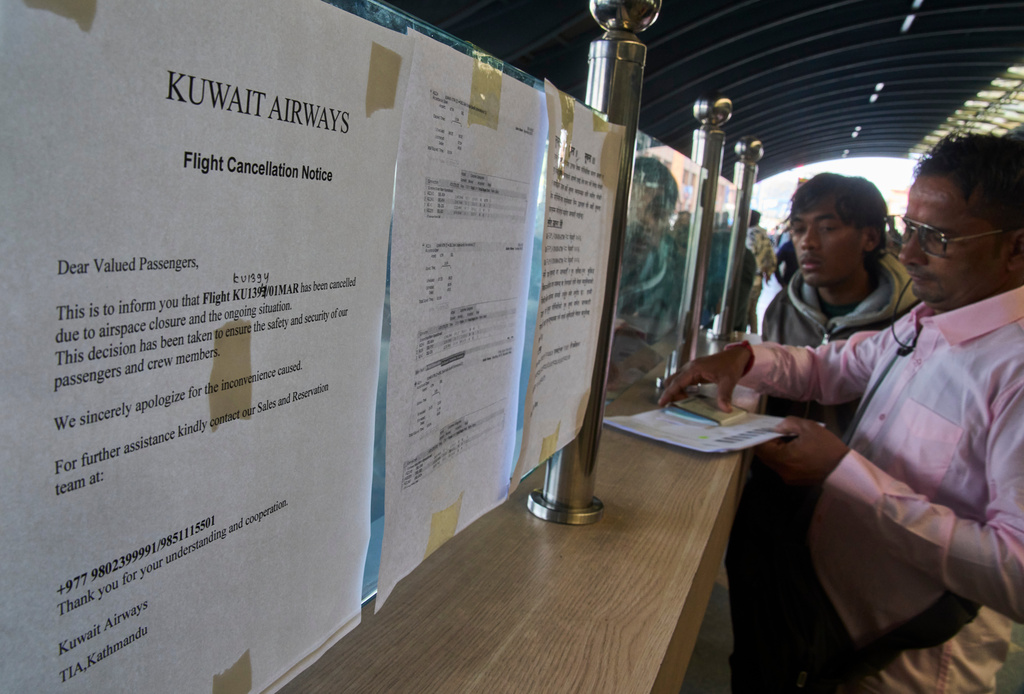 Nepalese migrant workers en route to the Middle East check flight detail after their flight was disrupted by regional airspace closures following escalating tensions and reported military strikes involving Iran, Israel and the United States, in Kathmandu, Nepal, Sunday, March 1, 2026. (AP Photo/Niranjan Shrestha)