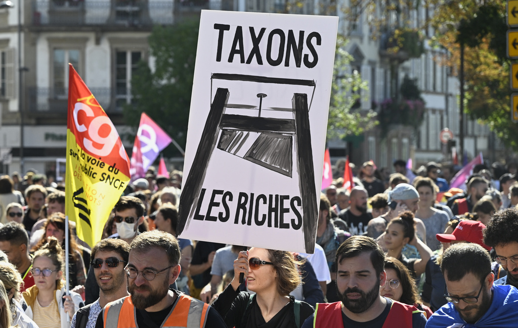 A protester holds a placard that reads, "let's tax the rich," during a rally of the "Block Everything" movement in Strasbourg, eastern France, Wednesday, Sept. 10, 2025. (AP Photo/Pascal Bastien)