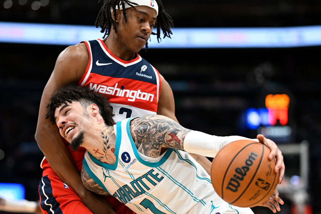 Charlotte Hornets guard LaMelo Ball (1) drives to the basket against Washington Wizards guard Tre Johnson, top, during the first half of an NBA basketball game Sunday, Oct. 26, 2025, in Washington. (AP Photo/John McDonnell)