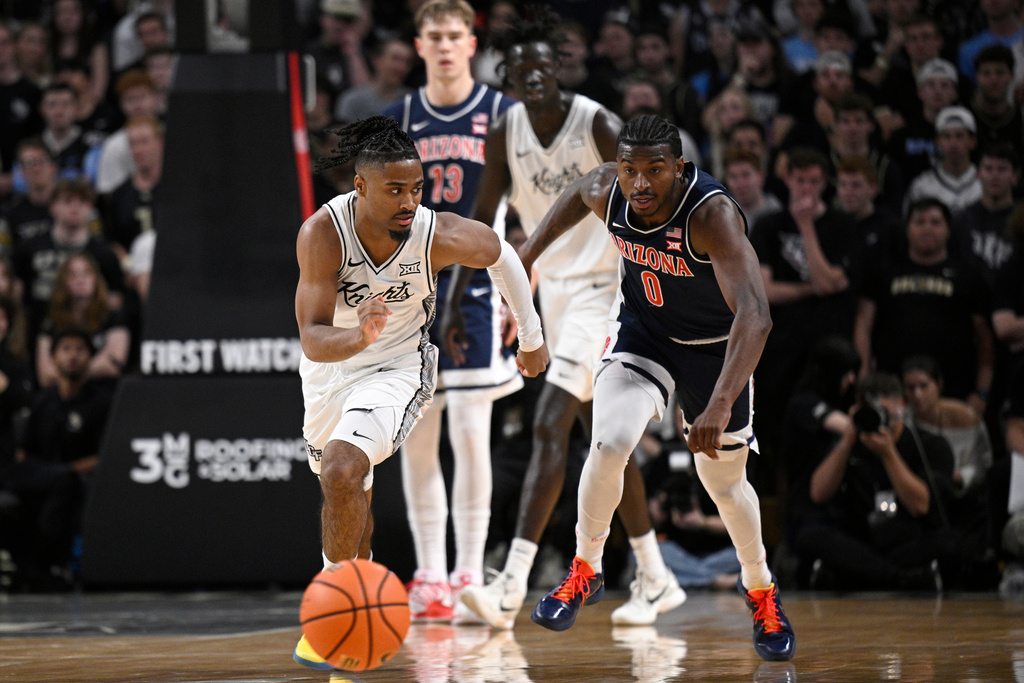 Central Florida guard Themus Fulks, left, chases down a loose ball against Arizona guard Jaden Bradley (0) during the first half of an NCAA college basketball game, Saturday, Jan. 17, 2026, in Orlando, Fla. (AP Photo/Phelan M. Ebenhack)
