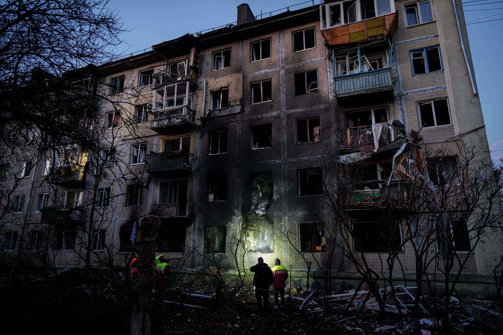 Municipal workers look at a residential building damaged after a Russian attack on Kyiv, Ukraine, on Friday, Nov. 14, 2025. (AP Photo/Evgeniy Maloletka)