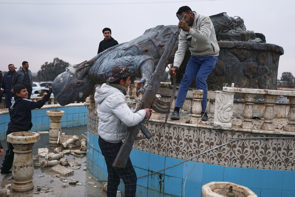 Residents topple a statue of a female Kurdish fighter after the takeover of the town by Syrian government forces from U.S.-backed Syrian Democratic Forces (SDF), in Tabqa, eastern Syria, Sunday, Jan. 18, 2026. (AP Photo/Ghaith Alsayed)