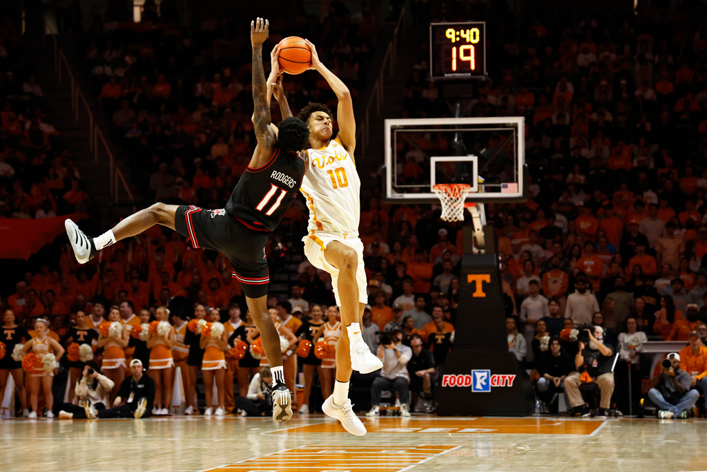 Tennessee forward Nate Ament (10) fights for the ball with Louisville guard Kobe Rodgers (11) during the first half of an NCAA college basketball game Tuesday, Dec. 16, 2025, in Knoxville, Tenn. (AP Photo/Wade Payne)