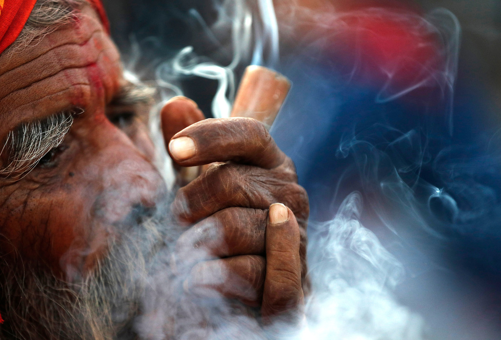 FILE- In this March 11, 2021, file photo, a Hindu holy man smokes marijuana in the courtyard of Pashupatinath temple during Shivratri festival in Kathmandu, Nepal. (AP Photo/Niranjan Shrestha, File)