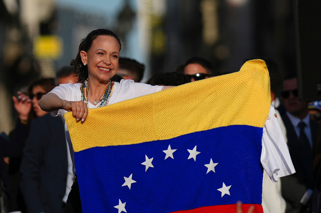 Venezuela's opposition leader Maria Corina Machado holds a Venezuelan flag on stage in front of supporters at Madrid's Puerta del Sol, in Madrid, Spain, Saturday, April 18, 2026. (AP Photo/Manu Fernandez)