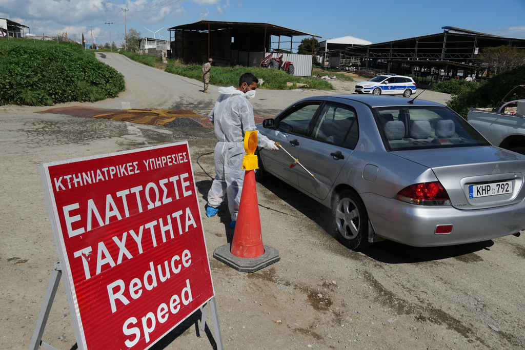 An employee sprays a car inside a blocked section of a livestock zone containing thousands of goats, sheep, and cows following an outbreak of foot-and-mouth disease in the Kelia area near Larnaca, Cyprus, Wednesday, Feb. 25, 2026. (AP Photo/Petros Karadjias)