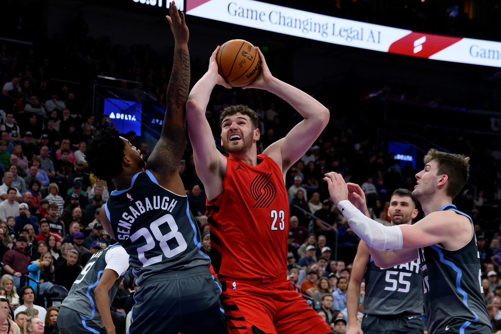 Portland Trail Blazers center Donovan Clingan, center, goes to the basket guarded by Utah Jazz forward Brice Sensabaugh, left, and Utah Jazz forward Kyle Filipowski, right, during the first half of an NBA basketball game, Thursday, Feb. 12, 2026, in Salt Lake City. (AP Photo/Tyler Tate)