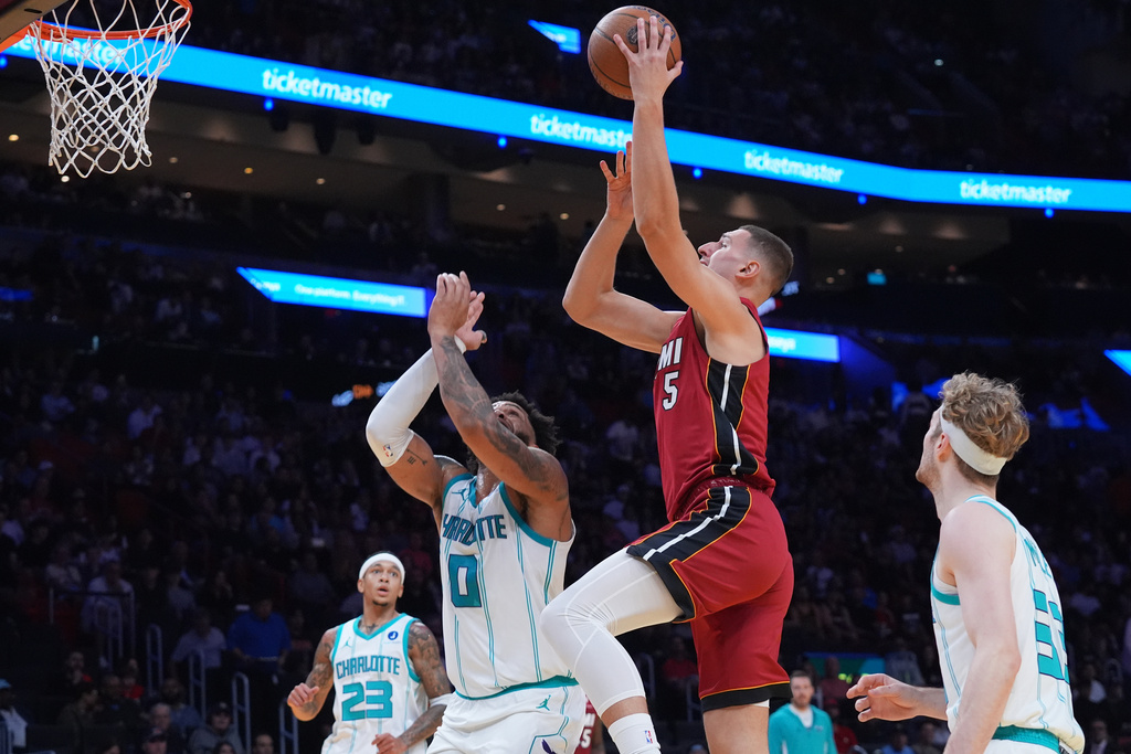 Miami Heat guard Pelle Larsson (9) drives to the basket over Charlotte Hornets forward Miles Bridges (0) during the first half of an NBA Cup basketball game Friday, Nov. 7, 2025, in Miami. (AP Photo/Marta Lavandier)