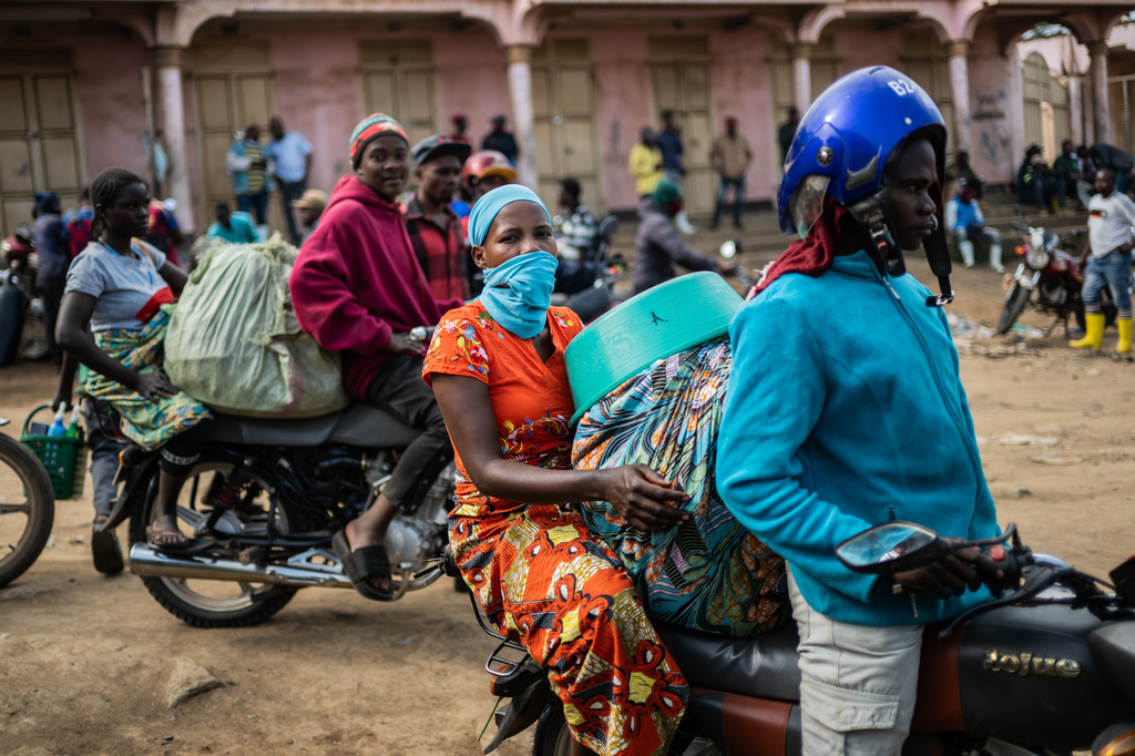 Motorcycle taxi riders and their passengers wait at the entrance to the central market while sanitation workers disinfect the area, as Ituri province continues to combat an Ebola outbreak in Bunia, Congo, Saturday, May 23, 2026. (AP Photo/Moses Sawasawa)