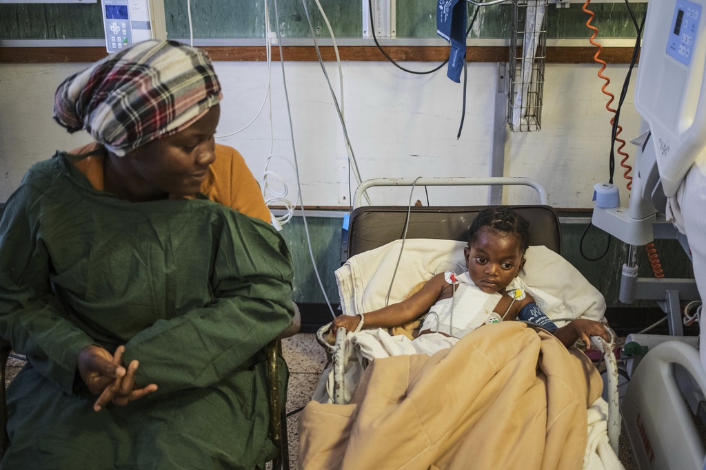 Vimbainashe Chakanungwa, left, watches on as her 9 year-old daughter Graciuos Chikovo sits on the chair as she recovers as she recovers from an open-heart surgery at Parirenyatwa Hospital, Harare, Zimbabwe, Thursday, July 17, 2025. (AP Photo/Aaron Ufumeli)