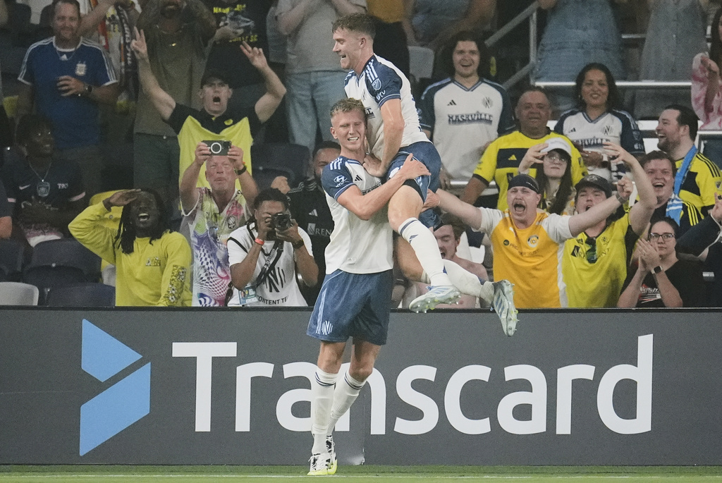 Nashville SC defender Josh Bauer, right, congratulates forward Sam Surridge, left, after scoring a goal during the first half of an MLS soccer match against Orlando City, Saturday, Aug. 23, 2025, in Nashville, Tenn. (AP Photo/George Walker IV)