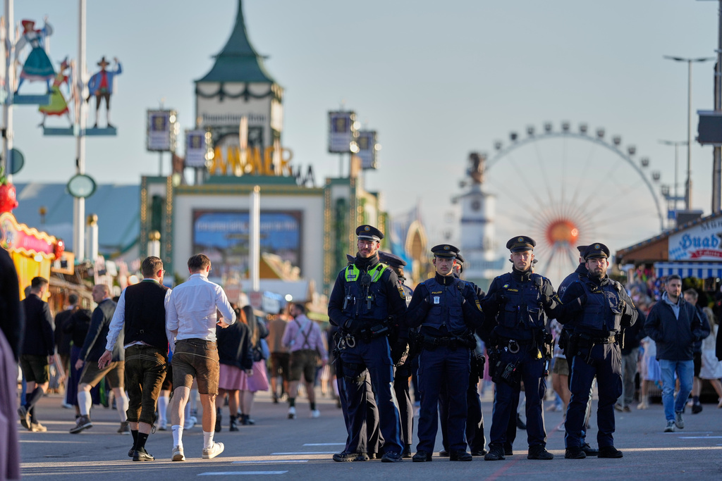 Visitors walk to the re-opening of the Oktoberfest watched by police officers that was closed since the morning after a bomb threatening in Munich, Germany, Wednesday, Oct.1, 2025. (AP Photo/Matthias Schrader)