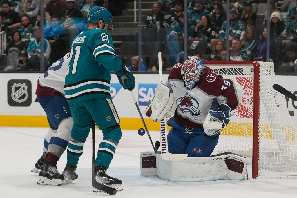 Colorado Avalanche goaltender Mackenzie Blackwood, right, defends against a shot next to San Jose Sharks center Alexander Wennberg (21) during the first period of an NHL hockey game in San Jose, Calif., Saturday, Nov. 1, 2025. (AP Photo/Jeff Chiu)
