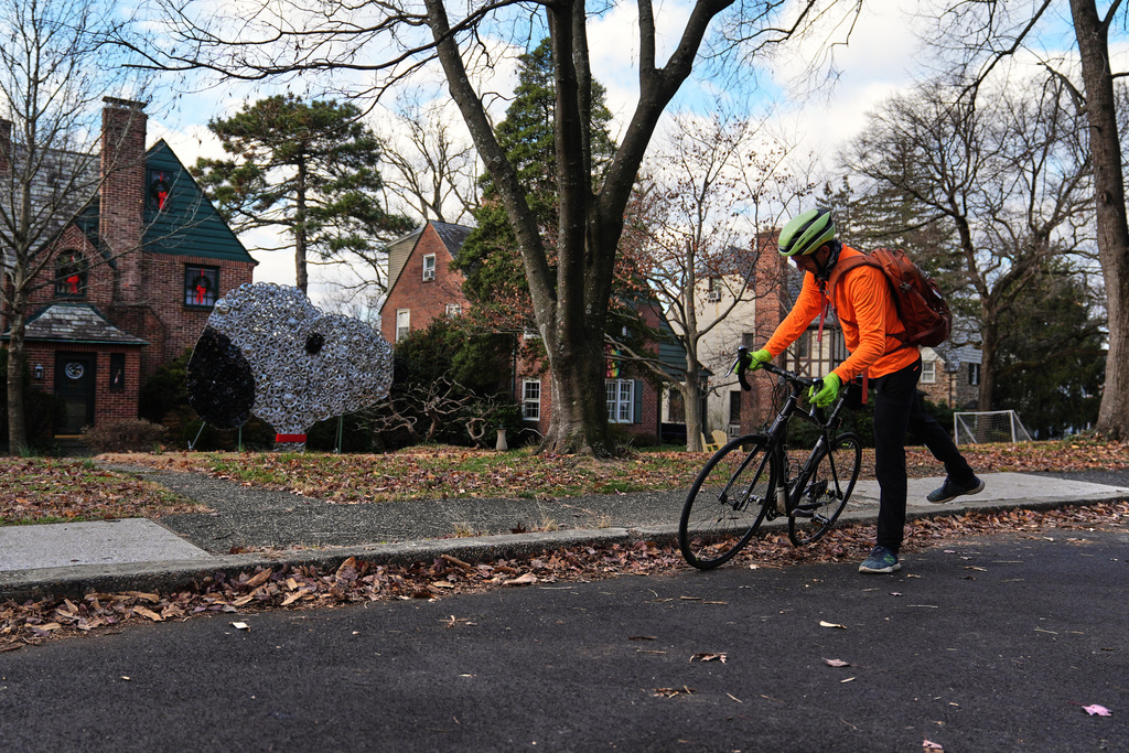 Cyclist Barnaby Wickham mounts his bike before riding off to collect lost hubcaps, Thursday, Dec. 11, 2025, in Baltimore. (AP Photo/Stephanie Scarbrough)