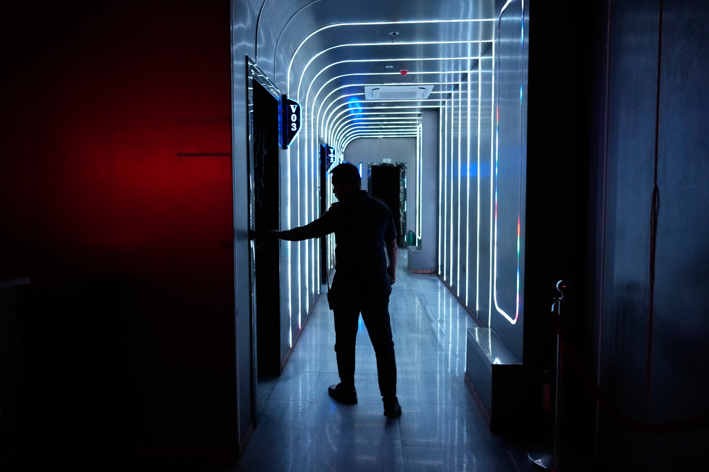 A man walks along what used to be karaoke rooms at a former scam compound that is now being used as the Presidential Anti-Organized Crime Commission temporary detention center for rescued scam workers in Pasay, Philippines, Wednesday, June 4, 2025. (AP Photo/Aaron Favila)