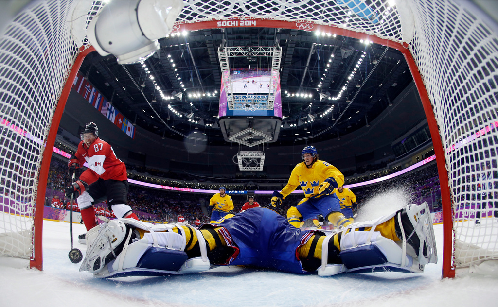 FILE - Canada forward Sidney Crosby, left, scores a goal past Sweden goaltender Henrik Lundqvist during the second period of the men's gold medal ice hockey game, Feb. 23, 2014, at the Winter Olympics in Sochi, Russia. (AP Photo/Julio Cortez, Pool, FIle)
