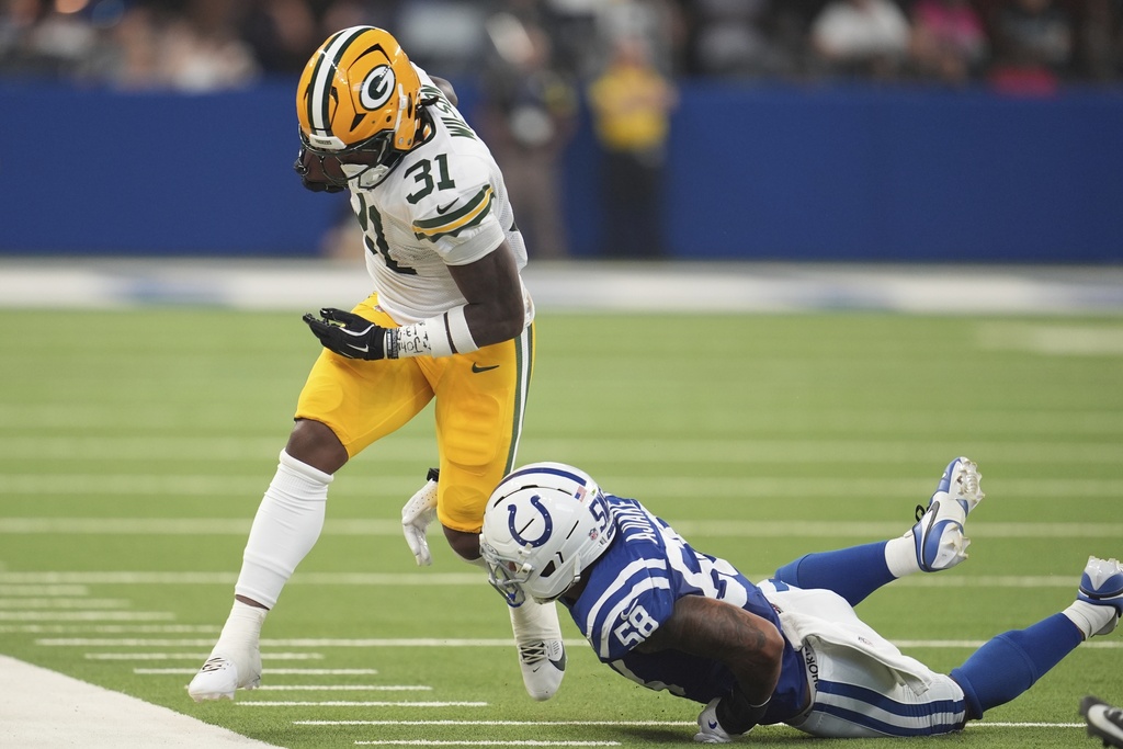 Green Bay Packers running back Emanuel Wilson (31) is tackled by Indianapolis Colts linebacker Austin Ajiake (58) during the first half of a preseason NFL football game, Saturday, Aug. 16, 2025, in Indianapolis. (AP Photo/Michael Conroy)