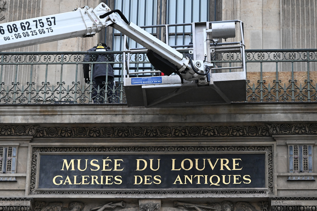 Workers install metal security bars over the window where thieves broke into the Louvre museum on Oct.19, Tuesday Dec.23, 2025 in Paris. (AP Photo/Emma Da Silva)