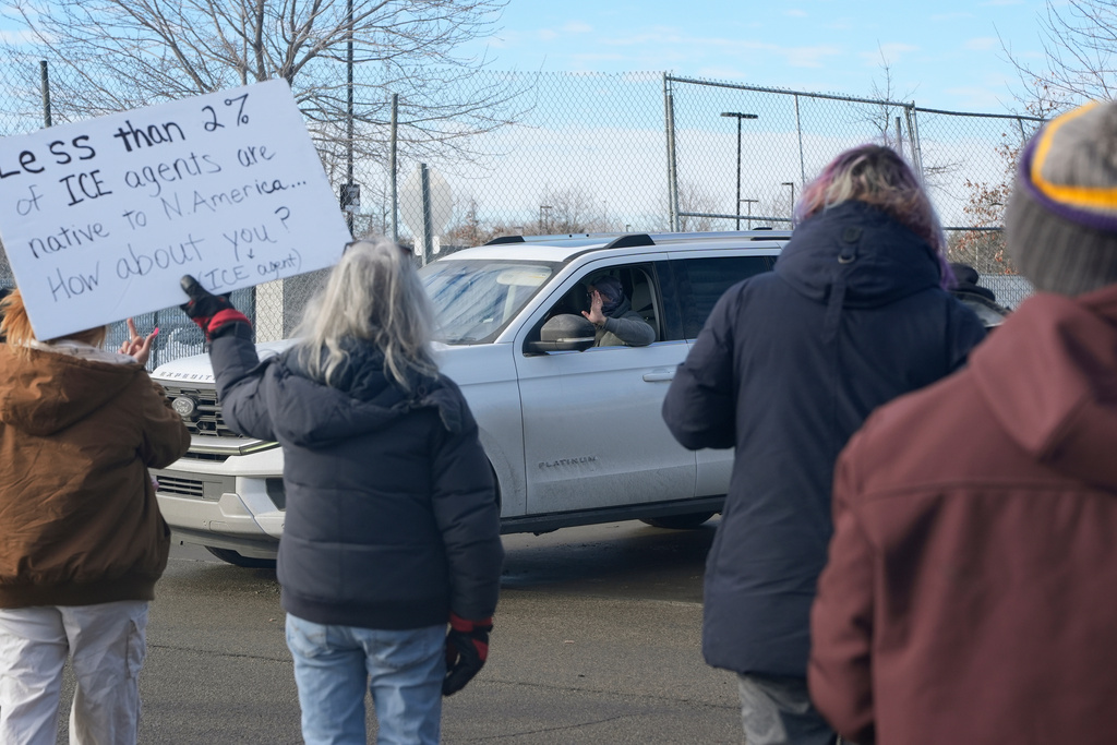 An Immigration and Customs Enforcement (ICE) agent waves at protesters while leaving the Bishop Whipple Federal Building, Monday, Jan. 12, 2026, in Minneapolis. (AP Photo/Jen Golbeck)