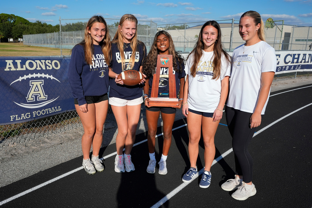 Alonso High School girls flag football players, from left, Mia Garcia, Shae Plantz, Natalie Fischer, Abigail Gabonay, and Gabriella Werr pose for a photo with their state championship trophy, Tuesday, Nov. 4, 2025, in Tampa, Fla. (AP Photo/Chris O'Meara)