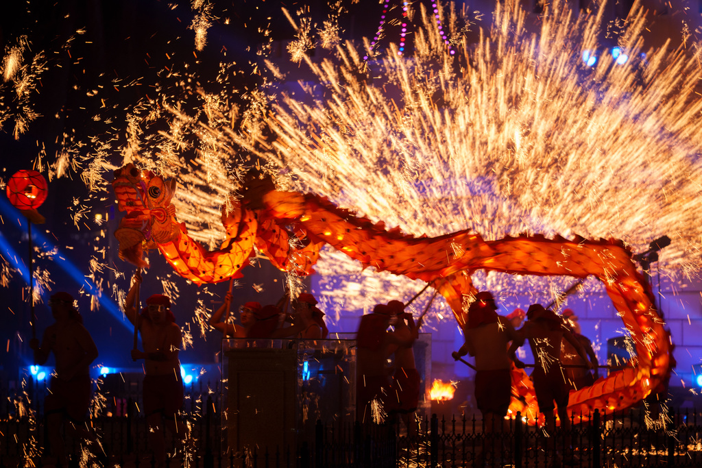 Fire performers carry a dragon during a molten iron fireworks performance known as "fire dragon steel flowers" ahead of Lunar New Year celebrations at an amusement park on the outskirts of Beijing, China, Saturday, Feb. 14, 2026. (AP Photo/Vincent Thian)