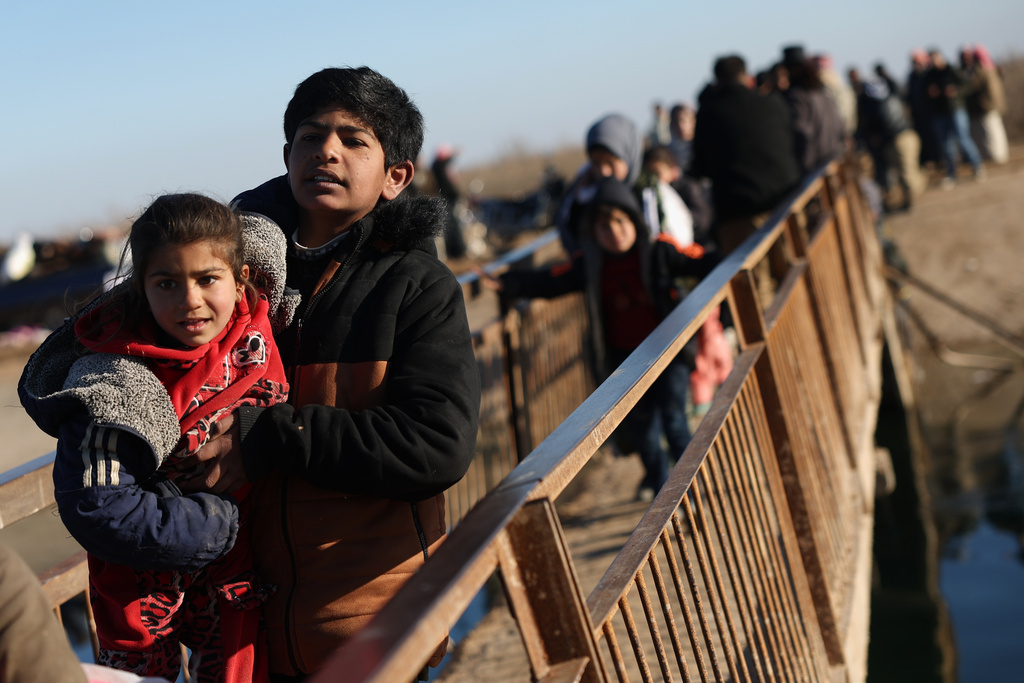 FILE - Displaced Syrians walk to cross at a river crossing near the village of Jarirat al Imam, in the eastern Aleppo countryside, near the front line with the Kurdish-led Syrian Democratic Forces in Deir Hafer, Syria, Thursday, Jan. 15, 2026. (AP Photo/Ghaith Alsayed)
