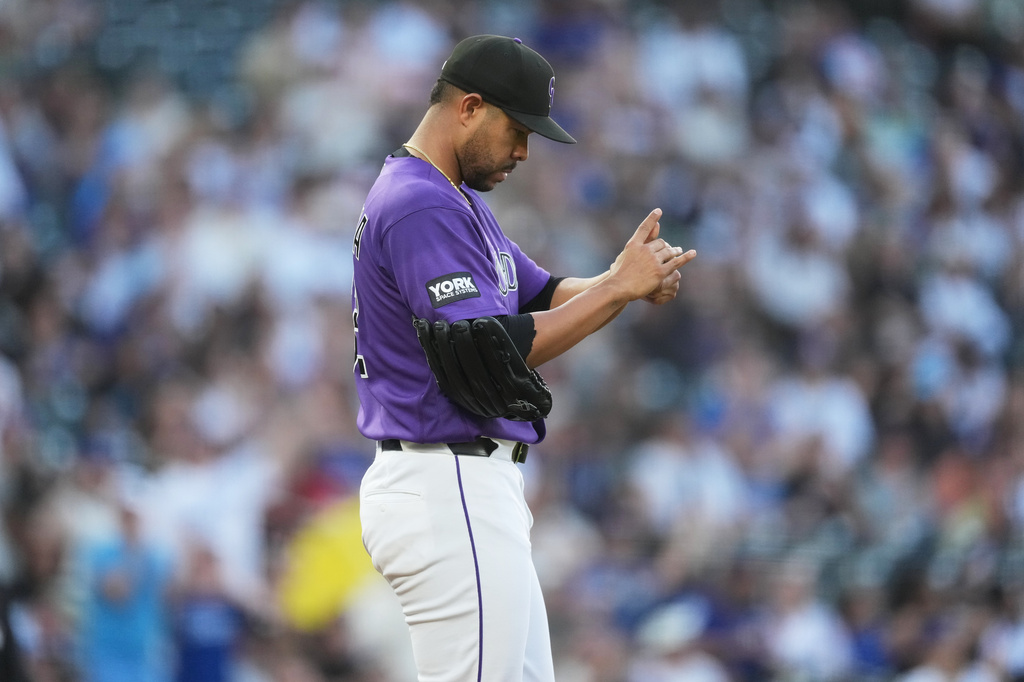 Colorado Rockies starting pitcher Jose Quintana rubs a new baseball after giving up a solo home run to Los Angeles Dodgers' Max Muncy in the second inning of a game Monday, April 20, 2026, in Denver. (AP Photo/David Zalubowski)