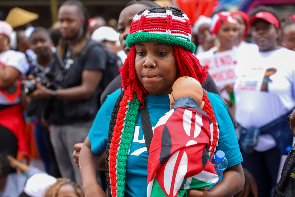 A demonstrator holds a doll wrapped in a Kenyan flag, during a march against rising cases of femicide, in downtown Nairobi, Kenya, on Monday, June 1, 2026. (AP Photo/Patrick Ngugi)
