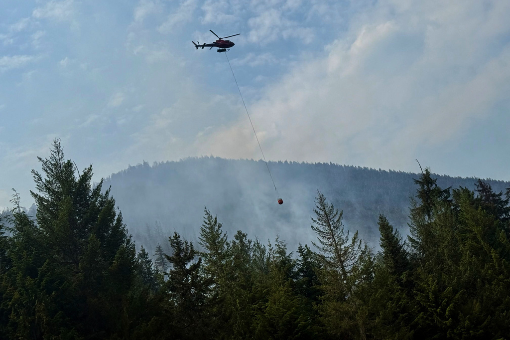 Fire crews drop water on a wildfire along Highway 3 in Manning Park, British Columbia, as fires burn throughout the southeastern part of the province on Wednesday, Aug. 12, 2026. (AP Photo/Haven Daley)