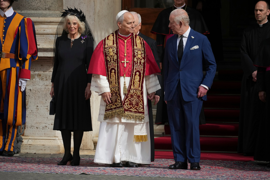 FILE - Pope Leo XIV, center, is flanked by Britain's King Charles III and Queen Camilla in the St. Damasus Courtyard at the Vatican after a state visit and a pray with him in the Sistine Chapel, Oct. 23, 2025. (AP Photo/Andrew Medichini, File )