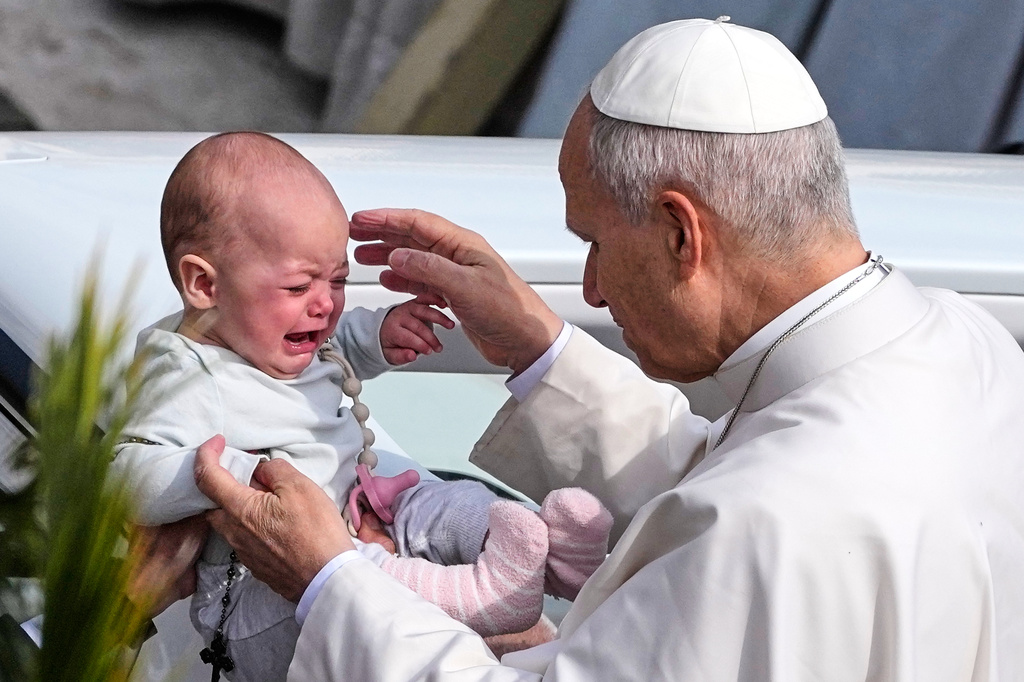 Pope Leo XIV caresses a child after presiding over Mass in St. Peter's Square at the Vatican on the Catholic feast of Palm Sunday, commemorating Jesus' arrival in Jerusalem, Sunday, March 29, 2026. (AP Photo/Alessandra Tarantino)