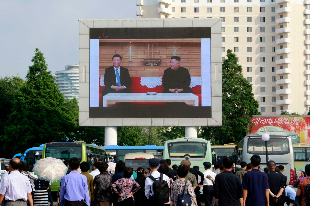 FILE - People watch a large screen showing an image of Chinese President Xi Jinping, left, meeting North Korean leader Kim Jong Un at Pyongyang Railway Station in Pyongyang, North Korea, Friday, June 21, 2019. (AP Photo/Jon Chol Jin, File)