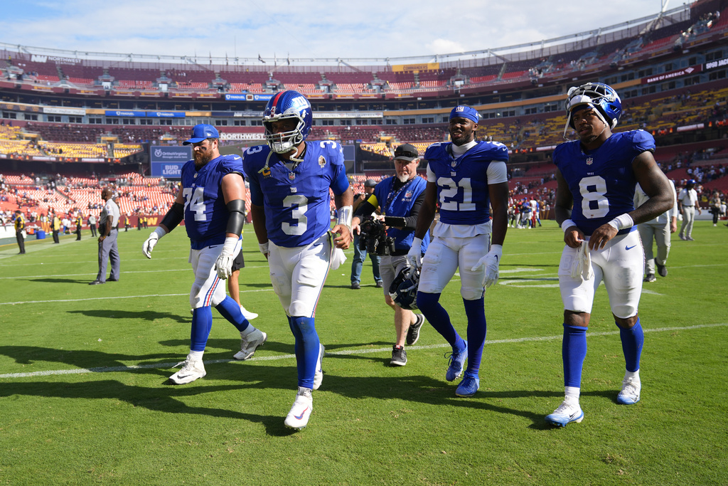 Walking off the field at the end of an NFL football game are from l-r., New York Giants guard Greg Van Roten (74), quarterback Russell Wilson (3), cornerback Paulson Adebo (21) and safety Jevon Holland (8), Sunday, Sept. 7, 2025, in Landover, Md. Commanders won 21-6. (AP Photo/Stephanie Scarbrough)