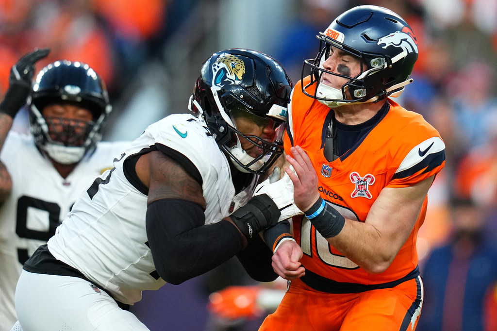 Jacksonville Jaguars defensive end Travon Walker, front left, tackles Denver Broncos quarterback Bo Nix, right, during the second half of an NFL football game in Denver, Sunday, Dec. 21, 2025. (AP Photo/Jack Dempsey)