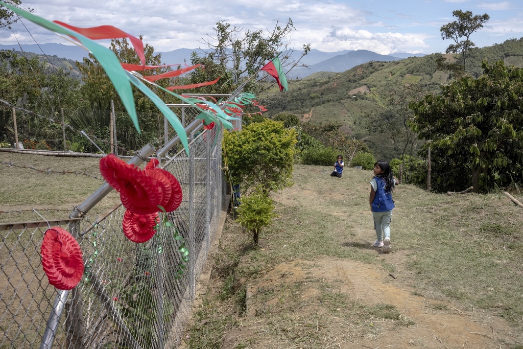 Children walk by decorations in the colors of red and green — which represent blood and earth, July 18, 2025, in Manuelico village, Caldono, Colombia. (AP Photo/Nadège Mazars)