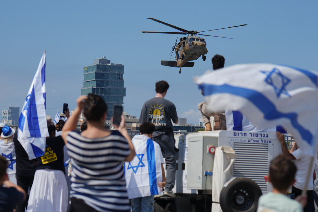 People wave Israeli flags as a military helicopter carrying Israeli freed hostages arrives at Beilinson hospital in Petah Tikva, Israel, after they were released from Hamas captivity in the Gaza Strip, Monday, Oct. 13, 2025. (AP Photo/Ariel Schalit)