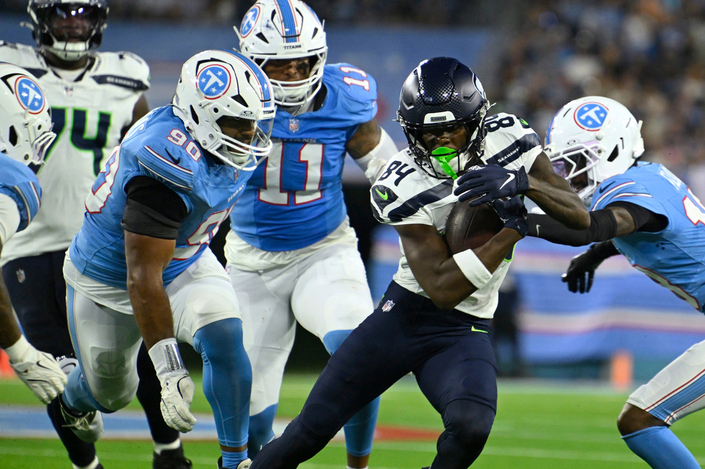 Seattle Seahawks wide receiver Emmanuel Henderson Jr. (84) runs from Tennessee Titans defensive tackle Solomon Thomas, left, and defensive back Cordale Flott, right, during the first half of a preseason NFL football game, Sunday, Aug. 23, 2026, in Nashville, Tenn. (AP Photo/John Amis)