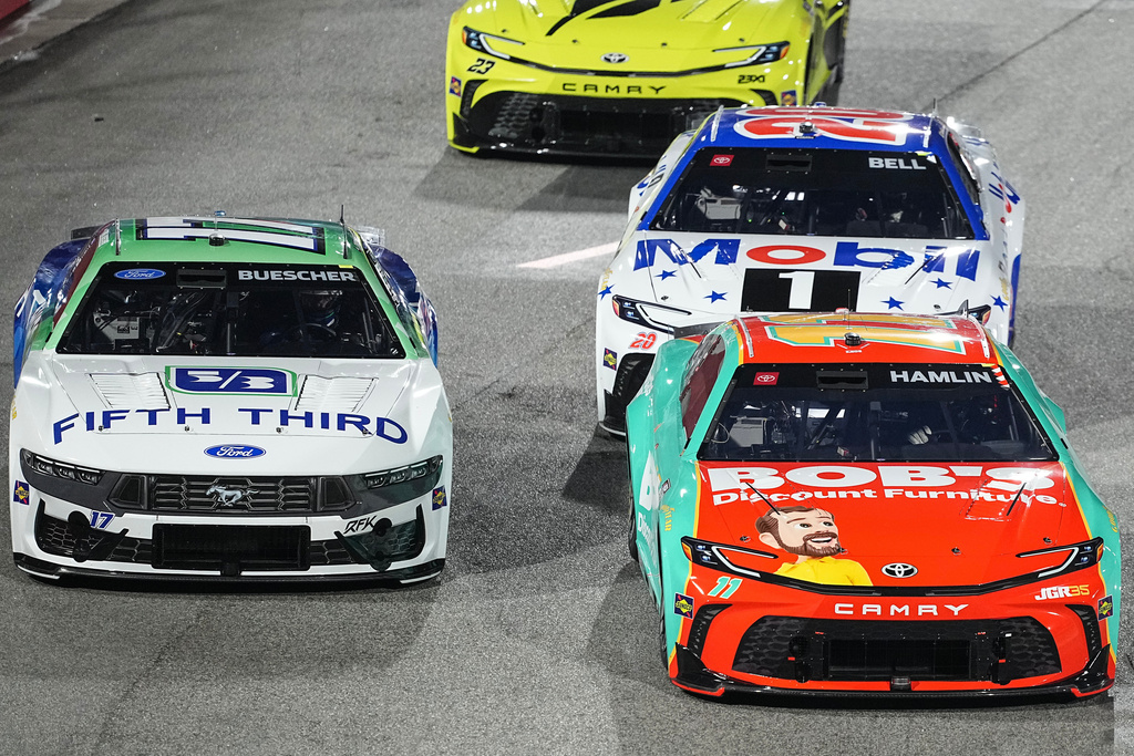 Denny Hamlin (11) passes Chris Buescher (17) in Turn 1 during NASCAR's The Clash preseason auto race at Bowman Gray Stadium, Wednesday, Feb. 4, 2026, in Winston-Salem, N.C. (AP Photo/Matt Kelley)