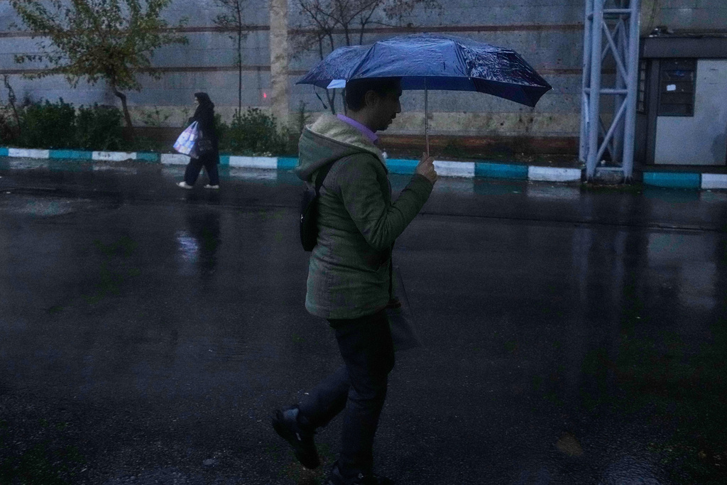 A man holds an umbrella while walking in bus station as rain falls in Tehran, Iran, Wednesday, Dec. 10, 2025. (AP Photo/Vahid Salemi)